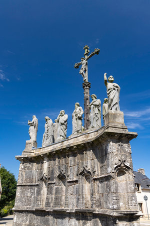 Impressive religious monument with statues of jesus on the cross and apostles, standing tall against a clear blue sky in Confort Meilars, Brittany, Franceの写真素材