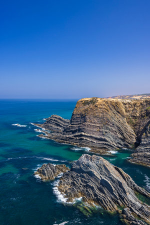 Beautiful rocky cliffs meeting the turquoise waters of the Atlantic Ocean on the coast of Odemira, Portugal, creating a spectacular natural landscapeの写真素材