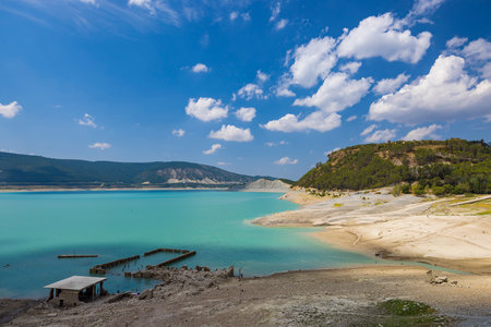 Scenic view of Yesa reservoir with turquoise water and dry, cracked land, highlighting the effects of drought in Aragon, Spainの写真素材