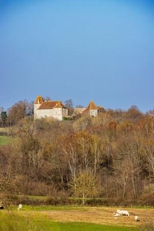 The Castle of Saint Firmin standing tall on a hill, surrounded by trees and fields in the French countrysideの写真素材