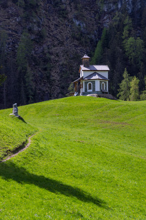 Small white chapel standing on a green hill in the valley of Pragraten am Grosvenediger in Tyrol, Austria, during a sunny summer dayの写真素材