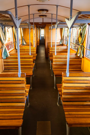Interior of an empty vintage train car with wooden seats and curtains, evoking a nostalgic atmosphere of past travelsの写真素材