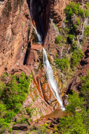 Cascading waterfall flowing down red rock formations in Guillaumes, a picturesque village in the Maritime Alps of Provence Alpes Cote d'Azur, showcases stunning natural beautyの写真素材