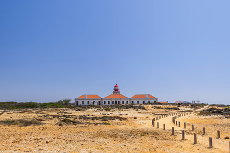 Scenic view of Cabo Sardao Lighthouse with its red top and white tower, located in Odemira, Portugal, on a sunny dayの写真素材