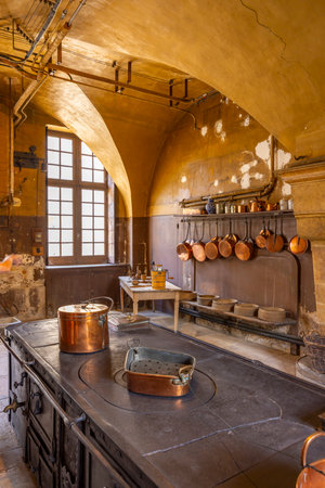 Copper pots and pans hanging in an old kitchen in Commarin Castle, Bourgogne Franche Comte, France, showing a glimpse into the pastの写真素材