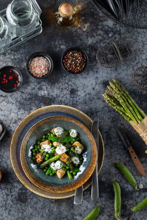 Spring salad with asparagus, peas, gnocchi and mozzarella cheese seasoned with spices on dark background is waiting to be eatenの写真素材