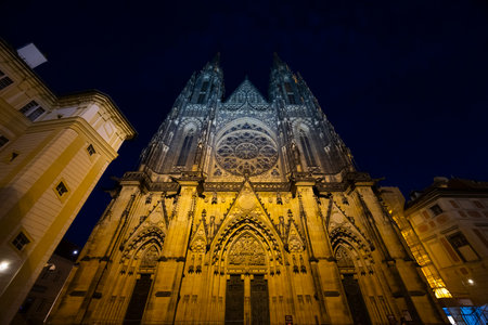 St. Vitus Cathedral standing tall against the night sky in Prague Castle, Czechia, illuminated by golden lightsの写真素材