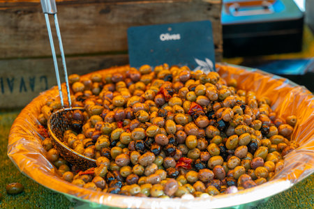 Colorful olives seasoned with herbs and chili peppers are displayed in a large bowl at a market in Nyons, Franceの写真素材