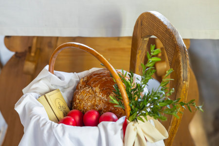 Traditional Easter basket with mazanec, red eggs, boxwood and prayer book resting on wooden chairの写真素材