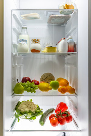 Open refrigerator full of various fresh and healthy food like milk, yogurt, fruits, vegetables and cheese, promoting a healthy lifestyleの写真素材