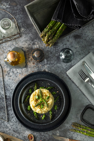 Creamy risotto with asparagus, olive oil, salt, and pepper on a marble table setting, creating a gourmet dining experienceの写真素材