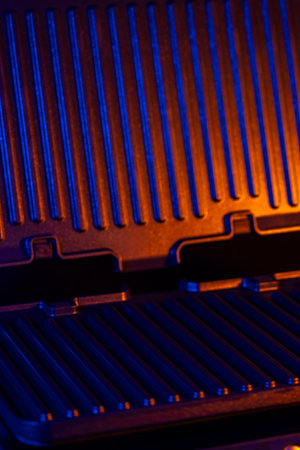 Modern electric grill illuminated with intense blue and orange light creating a dramatic atmosphereの写真素材