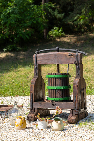 Old wooden wine press standing in a garden, surrounded by traditional pottery and glass jugs, in Slovakiaの写真素材