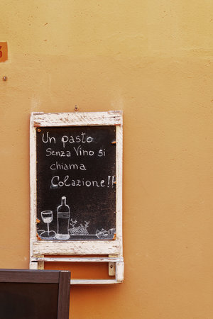 Blackboard sign in Assisi, Italy, humorously suggesting that a meal without wine is just breakfastの写真素材