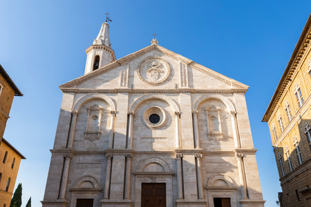 Renaissance architecture of the Duomo di Pienza in Pienza, Tuscany, Italy, showcasing its intricate facade and bell tower against a blue skyの写真素材