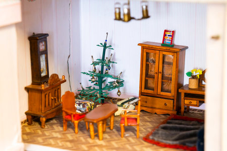 Miniature living room showcasing festive Christmas decorations, wooden furniture, and wrapped gifts under a charmingly decorated Christmas treeの写真素材