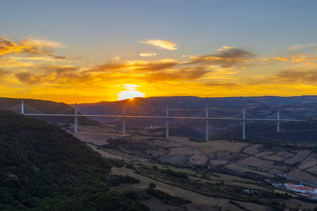 Majestic Millau Viaduct standing tall during a vibrant sunset over the picturesque Tarn Valley,...