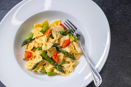 Farfalle pasta with green asparagus, cherry tomatoes and chickenの写真素材