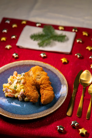 Holiday dinner table featuring traditional fried fish and potato salad, ready for festive celebrationの写真素材