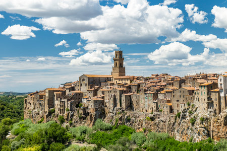 Pitigliano town built on a tufa cliff with its cathedral bell tower under a blue skyの写真素材