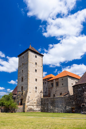 Medieval Svihov water castle with a tall tower and orange roof rising under blue sky with white clouds in Svihov, Czechiaの写真素材