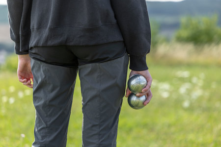 Person holding metal boules, playing outdoor game in Grand Est, Franceの写真素材