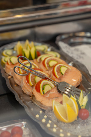 Salmon rolls prepared with fresh lemon and cucumber slices, presented on a silver platterの写真素材