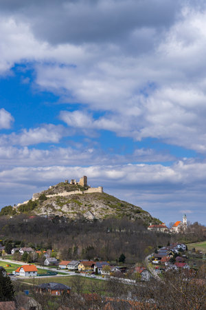 Staatz castle ruin towering over Enzersdorf bei Staatz village, Lower Austria, under a cloudy blue skyの写真素材