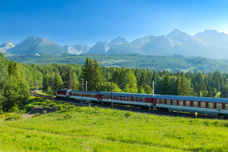 Traveling train in rural landscape with mountains and trees in Poprad, Slovakiaの写真素材