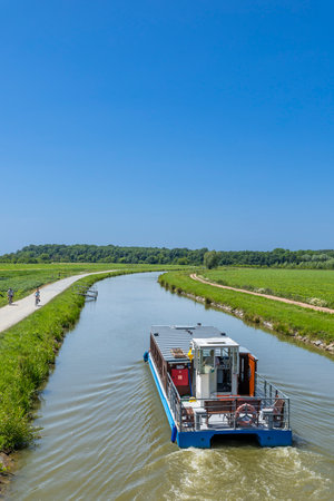 Boat cruises on the Bata canal in Vnorovy, Czechia, with people biking on the towpathの写真素材