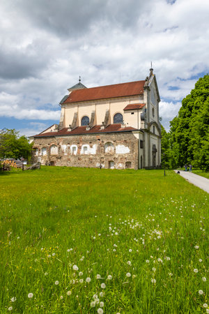 Historical monastery church building with crumbling stone walls next to lush green summer fieldの写真素材