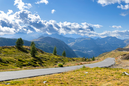 Asphalt road curving through rugged mountain landscape under a blue sky