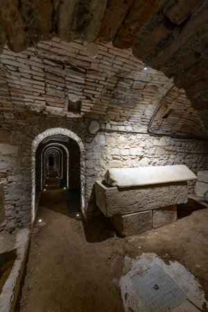 Ancient Roman underground passage featuring a stone sarcophagus and vaulted brick ceiling
