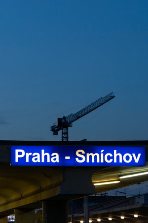 Glowing sign for Praha Smichov station against a blue evening sky with a craneの写真素材