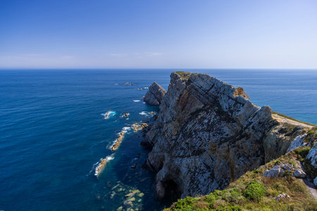 Rugged coastal landscape featuring steep cliffs meeting the blue Atlantic ocean under a clear skyの写真素材