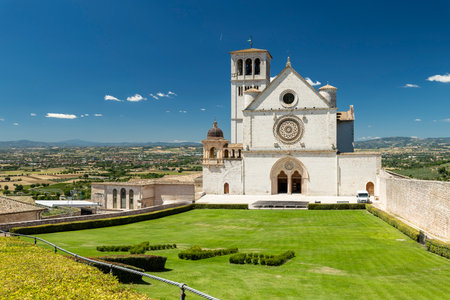 Historic Basilica di San Francesco d'Assisi standing above the valley under a blue skyの写真素材
