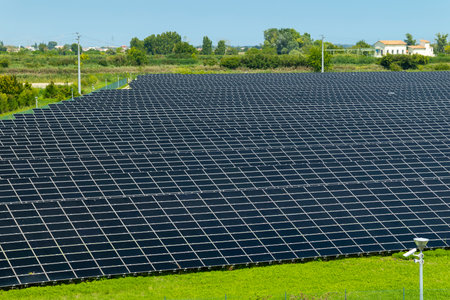 Large solar panel field producing renewable electricity under a clear blue sky in Loreo, Italy