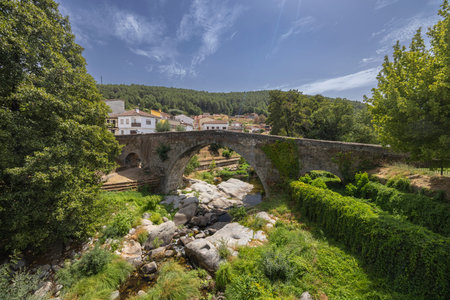 Historic arch bridge spanning a river near Arenas de San Pedro village in bright summer sun