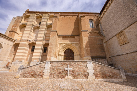 Historic Spanish monastery entrance featuring brickwork, archway, and religious stone cross
