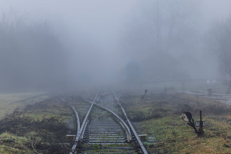 Railway junction and signal disappearing into dense fog, creating a mysterious, uncertain path