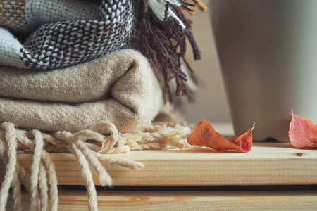 stack of beige checkered wool blankets and cup on a wooden chest. autumn concept of home warmth and comfort. tonedの写真素材