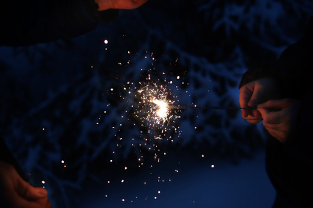 Sparkler in hands on the background of the night winter forest.の写真素材