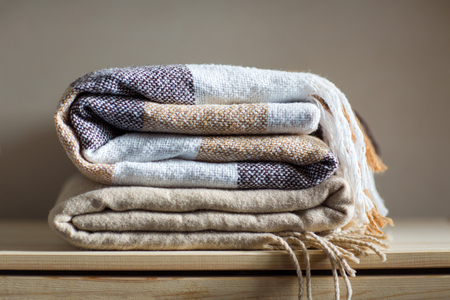 home textile. stack of beige wool blankets on a wooden shelf. autumn - winter concept of home warmth and comfort.の写真素材