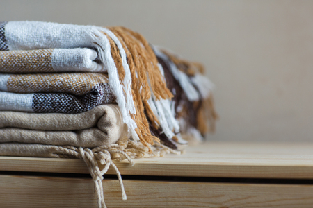 home textile. stack of beige wool blankets on a wooden shelf. autumn - winter concept of home warmth and comfort. copy spaceの写真素材