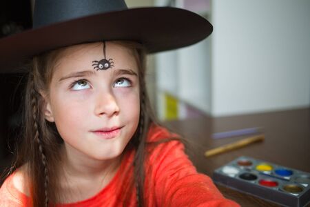 preparation for the celebration of Halloween. child in a witch outfit doing face painting. cute spider. idea of simple suit, diy, tonedの写真素材