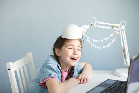 child student is fooling around. Happy young girl learns remotely. look at laptop. stay at home.