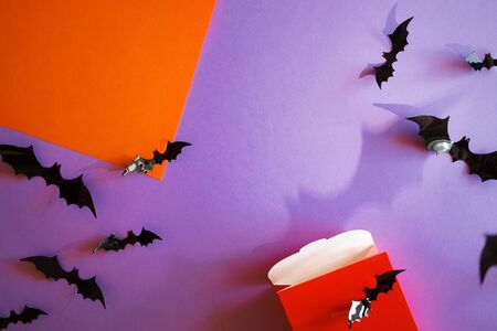 Halloween purple background with bats on orange paper. shadow . top view, copy space. open red giftの写真素材