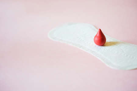 Menstrual daily sanitary pad with red drop of blood on pink background. Minimal concept care clean softの写真素材