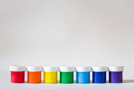 containers with paint in row on white background. multi-color acrylic rainbow. new gouache in banks.の写真素材