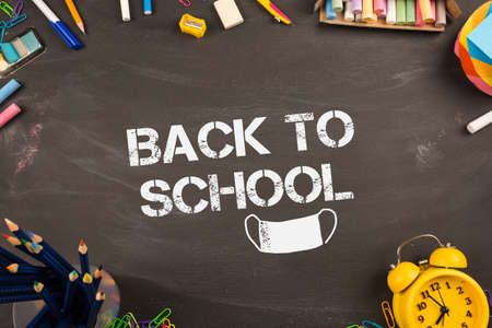 back to school text and mask of covid. school teacher's desk background.